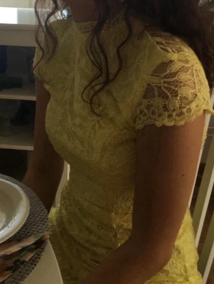 Gul lång spetsklänning med öppen rygg - Snygg gul långklänning i spets med hög hals och korta ärmar. Klänningen har en elegant öppen rygg och figurnära passform. Perfekt för dig som vill sticka ut med en unik och somrig look. Balklänning! Endast använd på balen. Var superbekväm och bra längd för mig som är 160 och hade klackar 😊från Nelly Eve