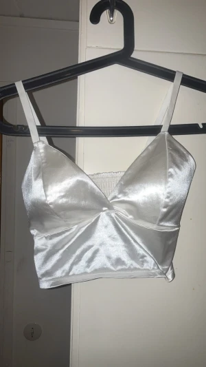 Vit & Champagne Rosa Satinlinnetopp - Snygg vit & Champagne Rosa linnetopp i satin med smala axelband och omlott-detalj framtill. Toppen har v-ringning och smockad rygg för extra komfort.