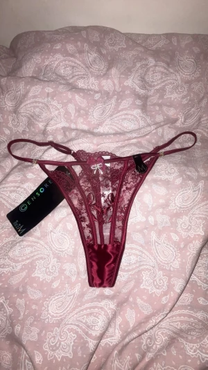 Vinröda spets stringtrosor - Ett par söta vinröda spets stringtrosor med en liten rosett framtill, helt nya, endast testat med andra underkläder under. Passar även som S.