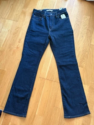 Mörkblå bootcut jeans från Levi's - Snygga mörkblå bootcut jeans från Levi's. Jeansen har en hög midja och är tillverkade i stretchigt denim för extra komfort. Perfekta för dig som gillar en tidlös och trendig look.