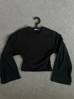 Svart croppad långärmad topp 157 - En svart lite croppad tröja ifrån Lager 157, tight i midjan och vida armar 💕