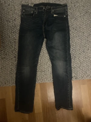 Levi's 510 mörkblå jeans - Säljer ett par Levi's 510 jeans i mörkblå tvätt med snyggt slitna detaljer. Klassisk femficksmodell med smal passform och raka ben. Tillverkade i mjukt och slitstarkt jeanstyg som sitter riktigt bra. Perfekta till sneakers eller boots.