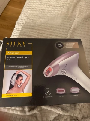 Silky Expert IPL hårborttagningsapparat - Silky Expert IPL hårborttagningsapparat i vitt och ljust rosa med svart display. Kommer med två olika munstycken för ansikte och kropp samt laddare. IPL-teknik med 5 intensitetsnivåer och 300 000 ljuspulser. Perfekt för smidig hårborttagning hemma. Använd endast ett par gånger.
