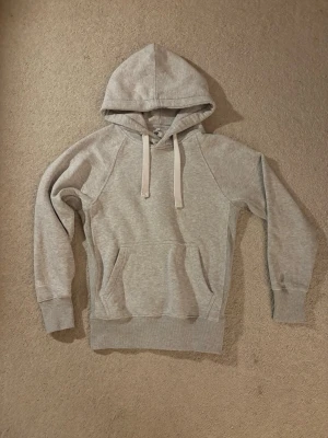 Grå hoodie från russemerch  - Säljer en snygg grå hoodie från russemerch. Hoodien är i storlek S och har tjockare vita snören vid luvan. Denna är riktig skön en kyligare vinter/höst dag eller när du bara vill ha på dig nått chill. Bara att skriva vid funderingar!