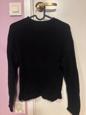 Svart ribbad stickad tröja Tom Tailor - Säljer en svart stickad tröja från Tom Tailor i storlek XS. Tröjan har ribbad struktur både på överdelen och ärmarna, samt en klassisk rund halsringning. Perfekt för dig som gillar enkel och stilren look.