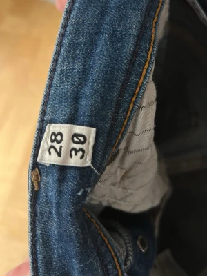 Blå jeansbyxor i rak modell - Säljer ett par klassiska blå jeansbyxor med snygg tvätt och kontrastsömmar. Modellen har raka ben och fem fickor, samt detaljerade sömmar på bakfickorna. Dem är i nyskick andvända 1 gång och är väldigt schysta 
