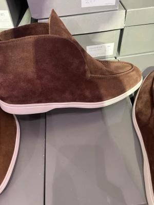 High loafers  - Säljer ett par helt nya stilrena loafers i brun mocka med vit, platt sula i storlek 43. Endast provade, aldrig använda. Nypris 3 600 kr.