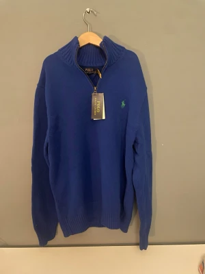 Blå stickad tröja Polo Ralph Lauren - Helt ny Ralph Lauren sip hoodie i blå färg. Denna tröja fick jag 3 år sedan i present och har inte använda den dess. Allting sitter kvar, tags och låda.  Nypris på denna kostade 2900kr. Mitt pris 1995 eftersom jag inte har kvitto till denna.