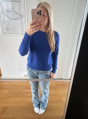 Blå basic stickad tröja H&M S - En enkel och stilren blå stickad tröja från H&M Basic. Tröjan har rund halsringning, ribbade muddar och är långärmad. Perfekt att matcha med jeans för en clean look.