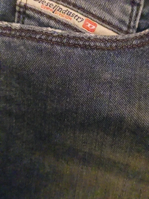 Mörkblå Diesel jeans straight fit - Säljer ett par mörkblå jeans från Diesel med klassisk femficksdesign och subtila slitningar framtill. Jeansen har en rak passform och snygga detaljer vid fickorna. Materialet är slitstarkt jeans och färgen har en schysst tvättad look.