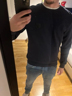Svart sweatshirt Antony Morato slim fit - Säljer en svart sweatshirt från Antony Morato i slim fit-modell. Tröjan har rund halsringning, diskret logga på bröstet och långa ärmar. Perfekt till jeans för en clean och stilren look.