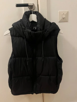 Väst från Zara - Snygg svart väst från Zara med luva.