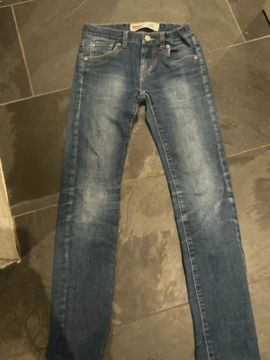 Feta Jeans med slitningar  - Säljer ett par klassiska Levis jeans med feta slitningar.  Passformen syns på bild 5.                         Storlek 152✅.                                                                  Hör av dig om du undrar något.