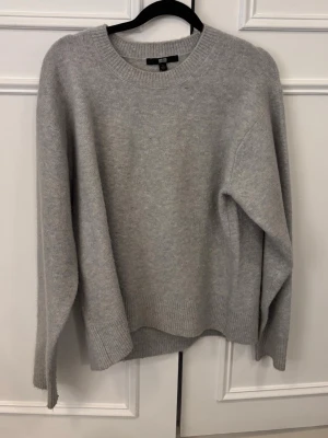 Grå stickad tröja från Uniqlo - Mysig ljusgrå stickad tröja från Uniqlo i storlek S. Tröjan har rund halsringning, ribbade muddar och en relaxed passform. Perfekt för lager på lager under kyliga dagar. Superbra kvalitet och skick!