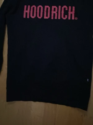 Svart sweatshirt från Hoodrich XS - Svart sweatshirt från Hoodrich i storlek XS. Tröjan har röd HOODRICH-logga tryckt framtill och är tillverkad i mjukt material. Klassisk passform med långa ärmar och rund hals. Perfekt för en chill och street-inspirerad look. Pris kan diskuteras, den har endast använts ett fåtal gånger.