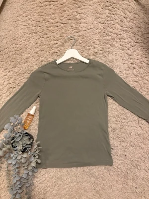 Grön långärmad topp från H&M - En enkel och stilren långärmad topp från H&M Basic i en olivgrön färg 