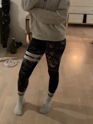 Stronger träningstights - Säljer ett par Stronger tights med märkblåish färg och mönster i lite olika färger. De har vita ränder runt ena låret( strongers vanliga). Tight passform och stretchigt material som passar perfekt till träning eller chill. Snygga och unika detaljer som sticker ut. Dessa är också endast använda ett fåtal gånger utan defekter🥰 skriv för mer info och bilder🥰 originalpris 799