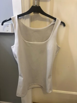 Vit linnetopp från Vero Moda - Säljer en enkel och stilren vit linnetopp från Vero Moda. Toppen har breda axelband och en fyrkantig ringning, vilket ger en modern look. Perfekt att matcha med jeans eller kjol för en clean outfit.