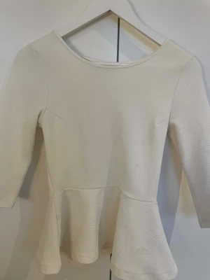 Vit peplumtop trekvartsärm - Säljer en jättefin vit peplumtop med trekvartsärm från Bikbok. Toppen har en rund halsringning och är gjord i ett strukturerat, lite tjockare tyg som ger en snygg form. Priset kan sänkas 💞💞