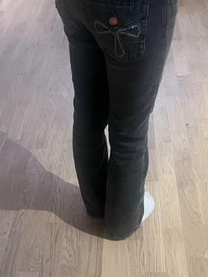 Svarta bootcut jeans med broderade fickor - Säljer ett par svarta jeans med bootcut-modell och låg midja. Byxorna har snygga detaljer på bakfickorna med dekorativa sömmar och knappstängning. Perfekta för dig som gillar en avslappnad men ändå trendig look. Från Gina tricot i storlek 158. De är svarta/mörkgråa.