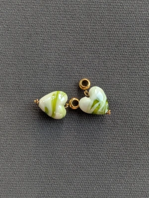 Hjärtformade örhängen i glas - Unika örhängen med hjärtformade hängen i vitt och grönt glas med swirl-mönster. Små guldfärgade detaljer och öglor ger en snygg finish. Perfekt för dig som gillar färg och personliga accessoarer.