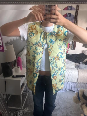 Mönstrad dunväst från Celine - Säljer en dunväst från Celine i färgglatt mönster. Västen har en loose passform och rundad halsringning. Perfekt statement-plagg för dig som vill sticka ut med lyxig vibe och cool vintagekänsla.