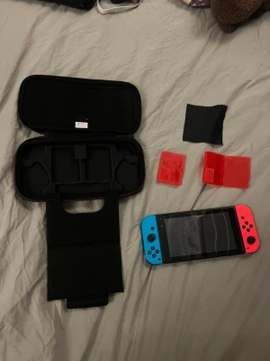 Nintendo Switch - Nintendo Switch med blå och röd Joy-Con, Super Mario-fodral, spelkorthållare och putsduk. Perfekt för barn och vuxna över 9 år.