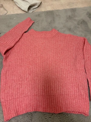 Rosa stickad tröja med ribbad kant - Mysig rosa stickad tröja med grov struktur och ribbad kant vid hals, ärmslut och nederkant. 