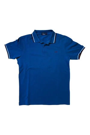Blå Fred Perry pikétröja S - Klassisk blå Fred Perry pikétröja med detaljer i vitt och vinrött på krage och ärmslut. Broderad logotyp på bröstet. Använd men fortfarande väldigt fint skick utan några skador! Axelbredd: 42 cm, längd: 65 cm.