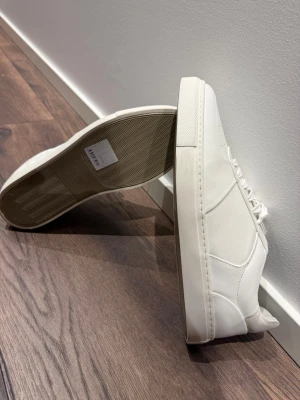 Vita sneakers från Filippa K i skinn - En ren och tidlös sneaker i mjukt skinn från Filippa K. Minimalistisk design, stabil sula och den där premiumkänslan som håller över tid.  Skick: Helt nya Storlek: 44 Färg: Vit Nypris: 2 500–3 000 kr The Label Drop pris:  1 700 kr  En kvalitetsmodell för dig som uppskattar diskreta detaljer, bra material och en look som fungerar till allt.  The Label Drop – Premium för alla. 