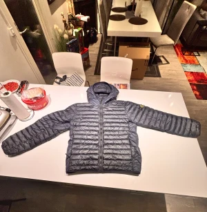 Mörkgrå dunjacka från Stone Island - Säljer en mörkgrå dunjacka från Stone Island som jag köpte från Nk 2023. Jag köpte jackan för runt 5000kr lite osäker på storlek, har för mig att de va mått och it storlek den ska passa 175cm men på något sätt passar mig perfekt som är 186, Jackan har ett litet jack på armen utan loggan men som är bra ihop sytt så man märker it riktigt. hör av er om ni har frågor