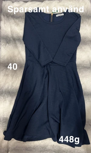 Marinblå klänning från Hampton Republic - Snygg marinblå klänning från Hampton Republic med rund hals och långärmade ärmar. Klänningen har en lätt utställd kjol och subtilt vågigt mönster i tyget. Dragkedja i ryggen för enkel på- och avklädning. Perfekt för dig som gillar stilren design.🌸 Sparsamt använd. Storlek 40