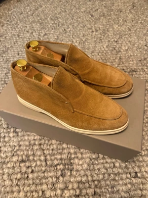 Rose and born open walk - Snygga skor i beige mocka med vit platt sula och rund tå. Skorna har en stilren slip-on design utan snörning och passar perfekt till en chill och clean look. Materialet är mjukt och ger en exklusiv känsla. Perfekt för dig som gillar klassisk stil.