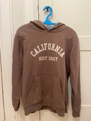 Brun hoodie  - Snygg brun hoodie från Kappahl. Tröjan har huva, magficka och långa ärmar. Passar 12-13Y.