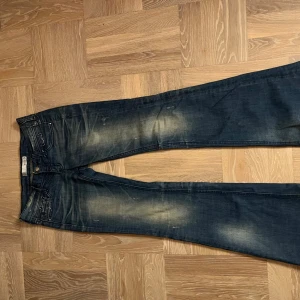 Blå jeans med strass från Three Roots - Snygga väldigt low waist blå jeans från Three Roots med coola slitningar och strassdetaljer på bakfickorna. Dom här är så jävla snygga!! Men tyvärr är de för små för mig så de har inte kommit till användning❤️