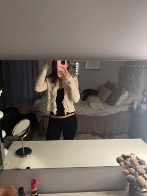 Beige stickad kofta med volang från Zara - Supersöt beige stickad kofta från Zara i storlek S. Koftan har ett öppet mönster, långärmad design och är croppad. Volangdetaljer längs kanten ger en extra girly vibe. Perfekt att slänga över en topp för en chill och stylish look.