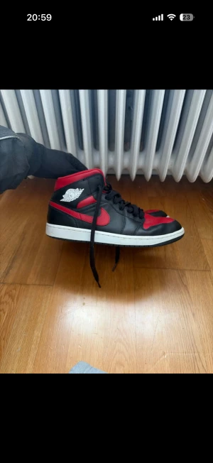 Nike Air Jordan 1 Bred Mids - Säljer köptes på nike Emporia ett par Nike Air Jordan 1 Mids i den klassiska Bred-färgen. Skorna är i svart och rött skinn med vit sula, röda swoosh och detaljer samt Air Jordan-logga på sidan. Perfekta för dig som vill sticka ut med ikoniska sneakers.
