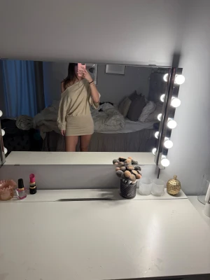 Beige offshoulder kort klänning - Snygg beige kort klänning med offshoulder och lös passform upptill. Klänningen har långa ärmar. Perfekt för dig som gillar en enkel men trendig look med lite extra edge. 