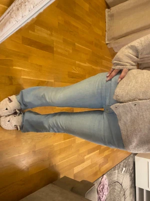 Bootcut ljusblå jeans från Gina - Säljer ett par ljusblå bootcut jeans från Levi's med klassisk femficksdesign och dragkedja. Jeansen har en snygg slitning längst ner på ena benet för en chill vibe. Passformen är normal och materialet är äkta jeansbomull.
