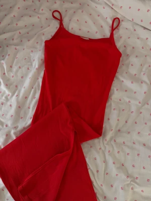 Röd ribbad klänning från Amisu -  röd ribbad klänning från Amisu med smala axelband och figurnära passform. Klänningen är ärmlös och har en enkel, stilren design. 