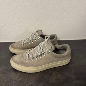 Grå mockasneakers från Diemme - Snygga sneakers från Diemme i grå mocka med vit platt sula och rund tå. Skorna har metallöglor och vita snören som ger en cool outdoor-vibe. Perfekt för dig som gillar stilrena och exklusiva sneakers med italiensk känsla. Storlek 41