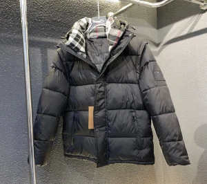 Svart pufferjacka med rutigt foder - Svart pufferjacka med rutigt foder i grått, vitt och rött. Jackan har huva, dragkedja och knappar framtill samt två fickor med dragkedja. Perfekt för kalla dagar och riktigt snygg med sitt klassiska rutmönster på insidan.