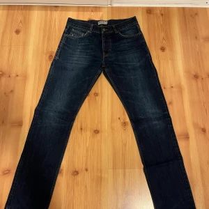 Mörkblå jeans från Dobber - Snygga mörkblå jeans från Dobber med klassisk femficksdesign och kontrastsömmar. Jeansen har rak passform och är tillverkade i slitstark denim med läderpatch bak i midjan. Perfekta för dig som gillar en tidlös och stilren look.