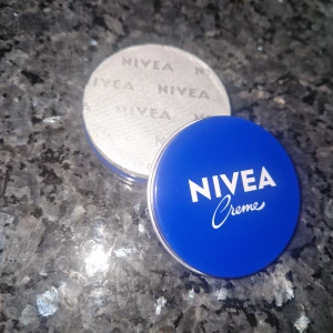 Nivea Kräm  - Nivea Creme i en rund blå plåtburk med vitt tryck, innehåller 30 ml återfuktande kräm. Perfekt att ha i väskan för daglig hudvård. 