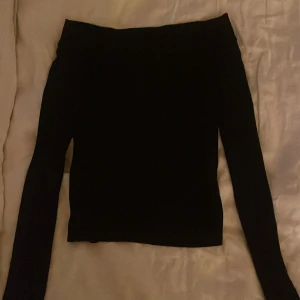 Svart offshoulder topp från Bikbok - Svart, stilren offshoulder topp från Bikbok i storlek S. Toppen har lång ärm och en tight passform som sitter snyggt över axlarna. Perfekt att styla med jeans eller kjol för en clean look. Materialet känns mjukt och stretchigt mot huden.