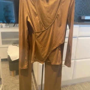 Bruna ribbade byxor i stretchigt tyg - Säljer ett par bruna ribbade byxor i stretchigt och mjukt material. Byxorna har en rak passform och hög midja, perfekta för en chill och trendig look. Färgen är varm brun och tyget är lätt och följsamt.