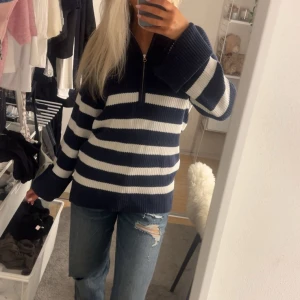 Randig stickad half zip tröja från bik bok - Mysig stickad tröja med breda marinblå och vita ränder. Tröjan har en half zip-dragkedja framtill och långa ärmar med breda muddar. Passformen är loose och materialet känns tjockt och skönt, perfekt för kyliga dagar. Jag är 168 för referens 