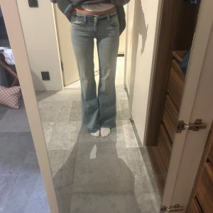 Ljusblå bootcut jeans - Säljer ett par ljusblå jeans med bootcut-modell och klassisk femficksdesign. Jeansen har låg midja och är tillverkade i mjukt denimtyg. Perfekta för dig som gillar en retro vibe och vill ha ett par snygga jeans med utsvängda ben.