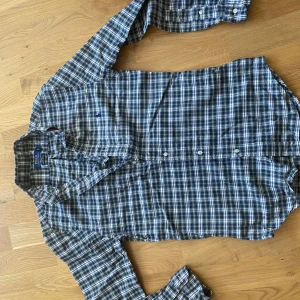 Rutig skjorta från Polo Ralph Lauren - Klassisk rutig skjorta i blått, vitt och grönt från Polo Ralph Lauren. Skjortan har lång ärm, knappar framtill och en liten broderad logga på bröstet. Perfekt för en avslappnad men ändå stilren look.