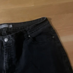 Svarta jeansbyxor från Mingel - Svarta jeansbyxor från Mingel med klassisk femficksdesign och silverfärgade nitar. Jeansen har en rak passform och är tillverkade i ett robust denimtyg. Perfekta för dig som gillar en enkel och stilren look.